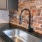 a kitchen with a sink and a brick wall